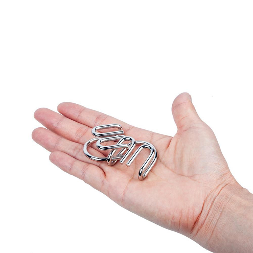 A hand holding a small metal puzzle with curved, interlocking pieces.