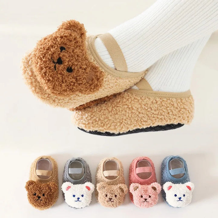Khaki bear baby slippers worn over white socks, with five color options shown below
