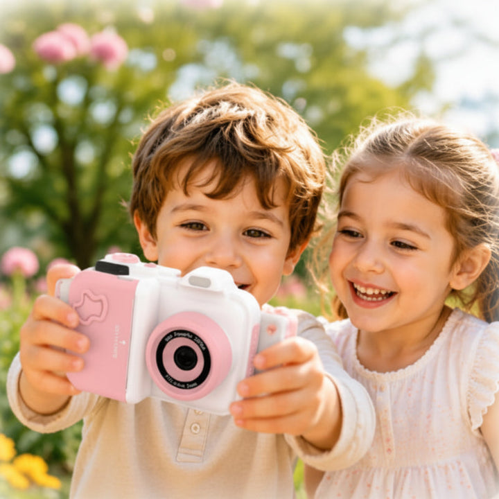 Two children holding a white-and-pink instant-print camera outdoors
