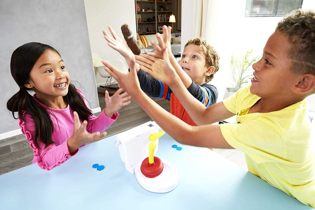 Three children with hands raised around a tabletop toilet game