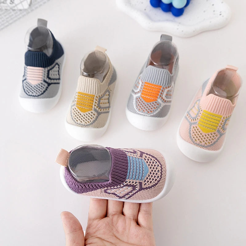 Purple knit slip-on shoe resting on a hand beside blue, beige, gray, and pink shoes