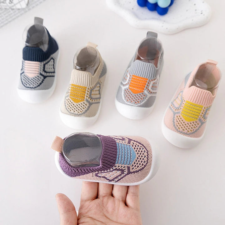 Purple knit slip-on shoe resting on a hand beside blue, beige, gray, and pink shoes