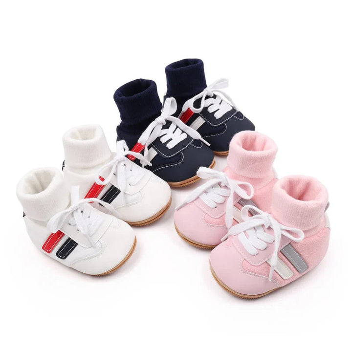 Navy, white, and pink baby shoes arranged to show lace-up fronts and ribbed ankle cuffs