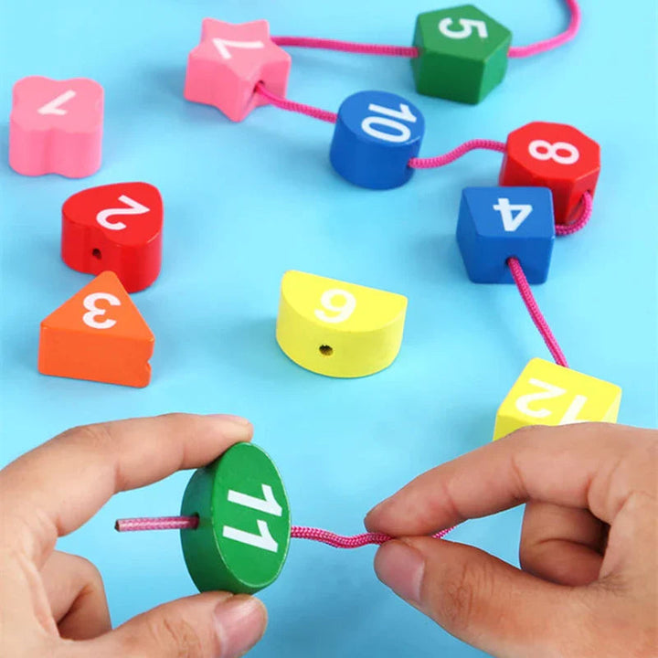 Hands threading a pink lace through the green number 11 block