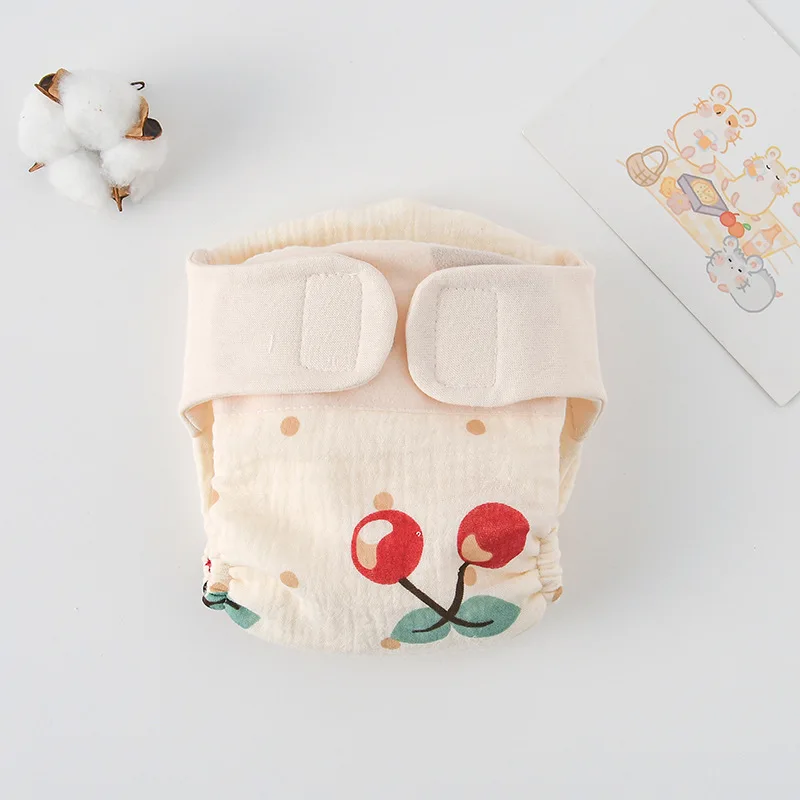 Cloth diaper with large red cherries and a cream hook-and-loop waistband