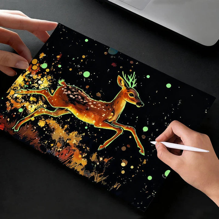 Hands scratching a colorful leaping deer design on a black scratch-art card