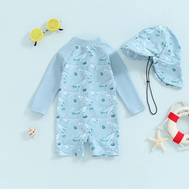 Light blue whale-print swimsuit with long sleeves and short legs beside its matching hat.