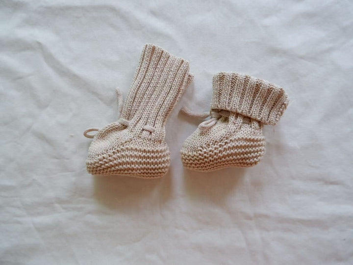 Light gray knitted baby booties showing an upright cuff and a folded cuff.