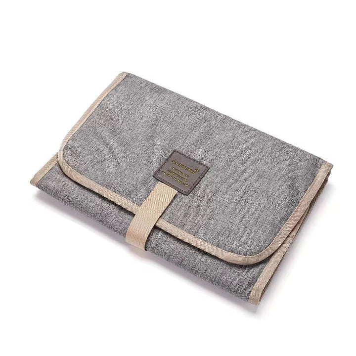 Light gray portable changing mat shown folded with its front closure strap