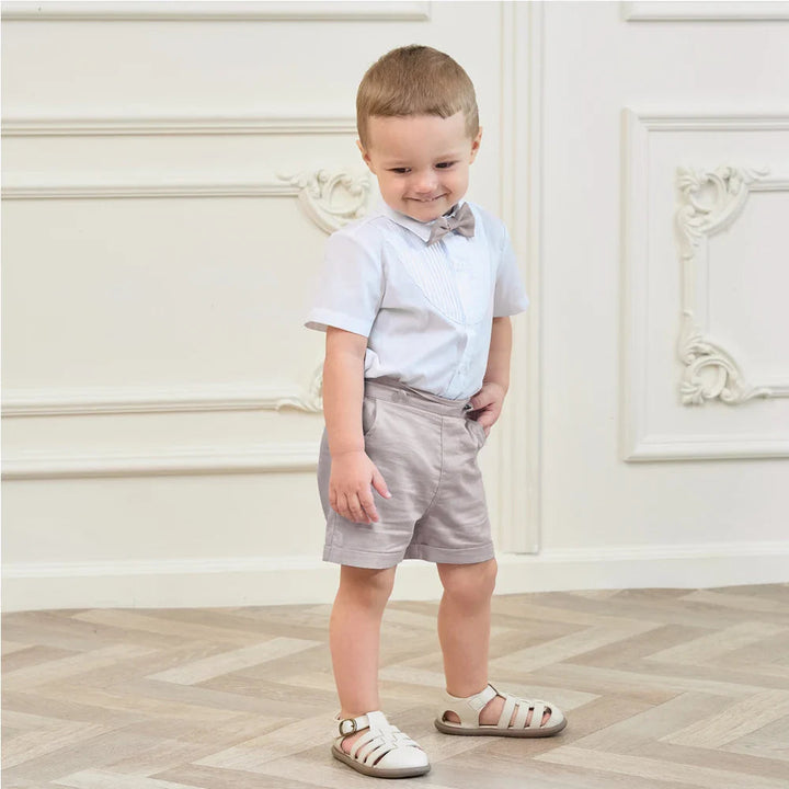 Boy modeling light-colored shorts with a white short-sleeve shirt and bow tie