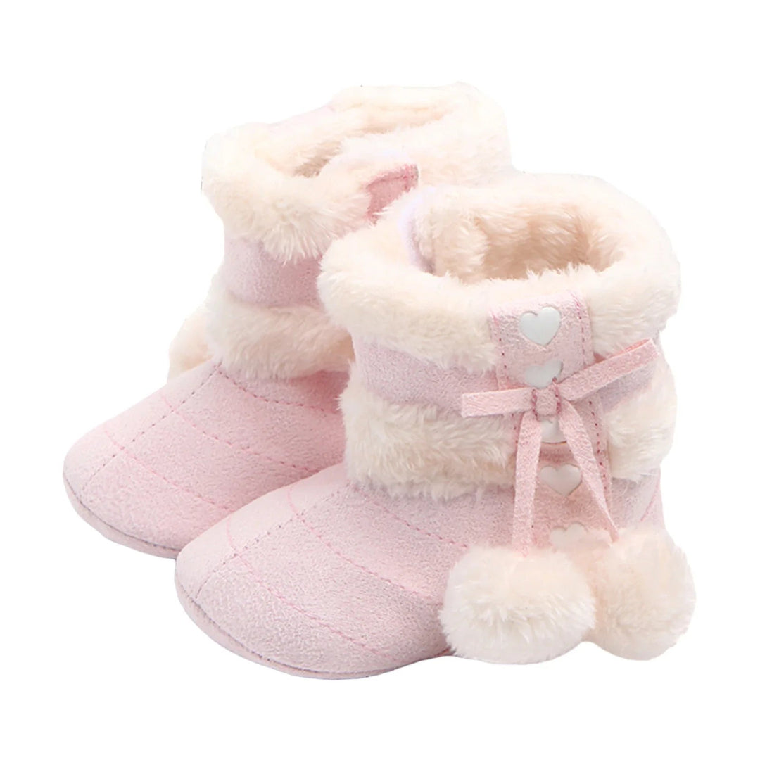Pair of light pink baby snow boots with heart accents and cream pom-poms