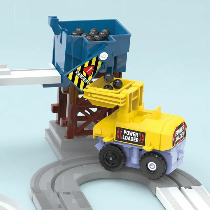 Yellow loader positioned beneath a blue hopper on the curved construction track