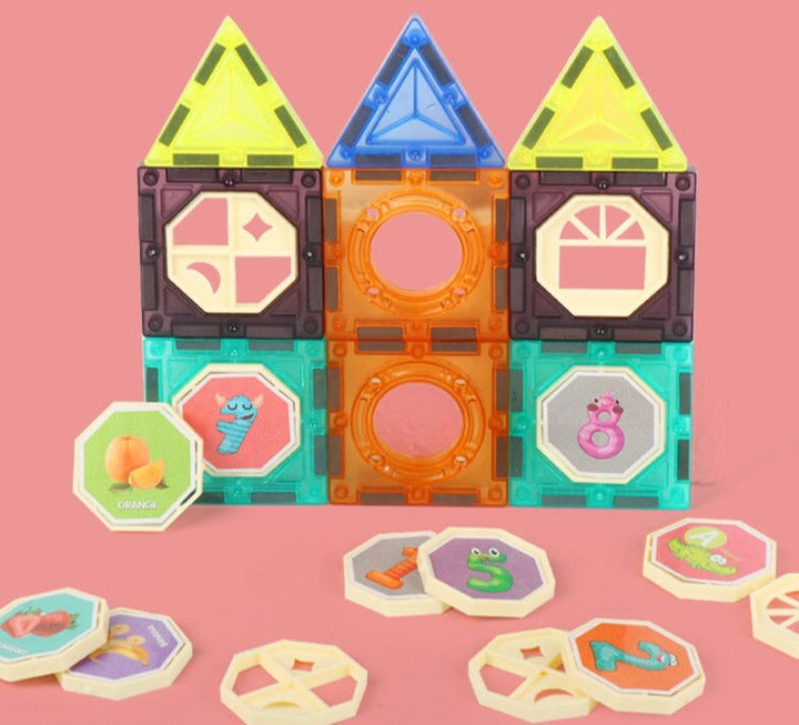 House-shaped arrangement of colorful magnetic tiles with illustrated inserts on a pink background.