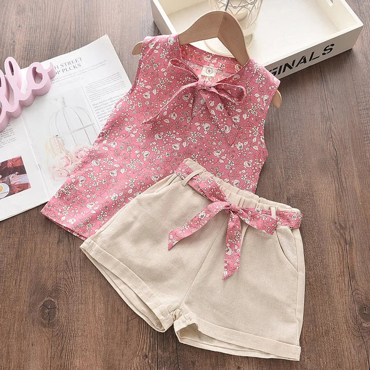 Pink floral sleeveless top paired with beige shorts and a pink floral waist tie