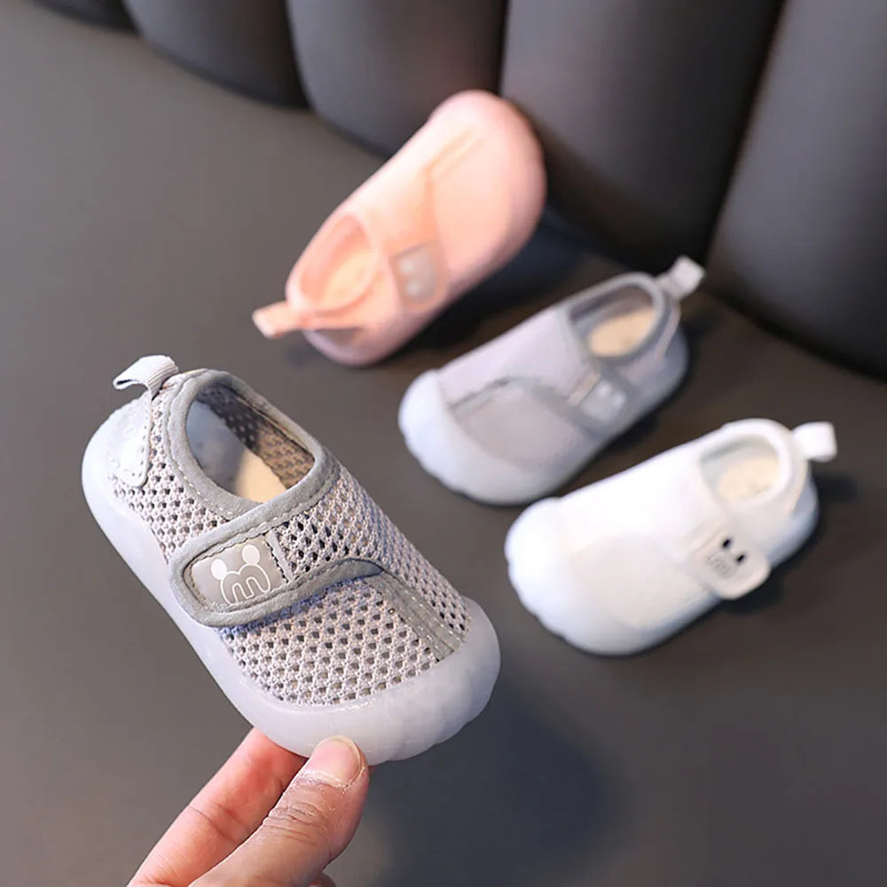 Gray mesh kids' shoe held in front of pink, gray, and white color options