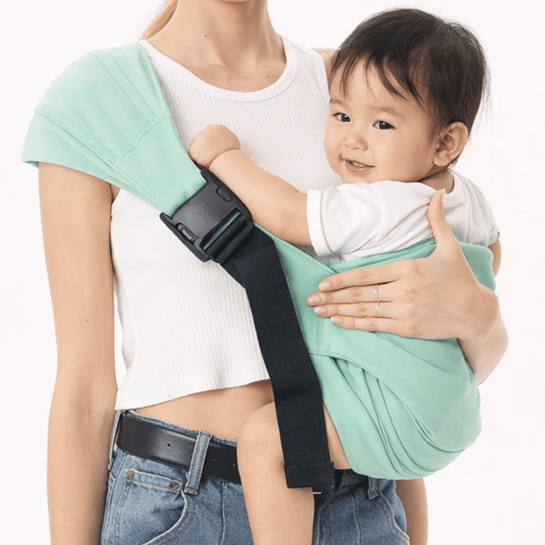 Close-up of a mint-green hip carrier worn across an adult's shoulder while carrying a child