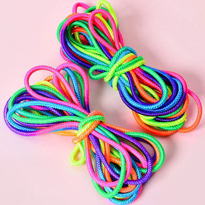 Two folded rainbow elastic jump band bundles on a pink background