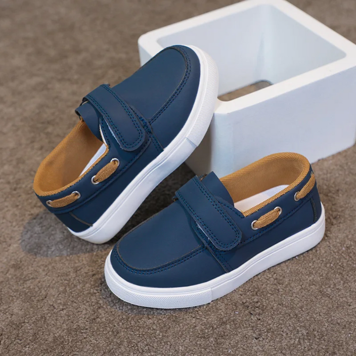 Navy blue loafer sneakers with tan lining, side cord details and white soles
