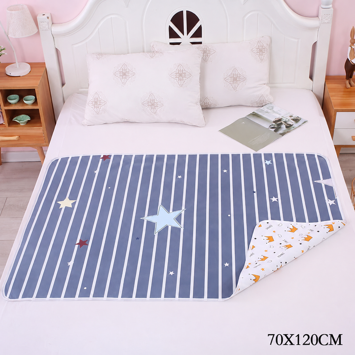 Navy star-and-stripe changing mat on a bed with one corner turned back, labeled 70 x 120 cm.