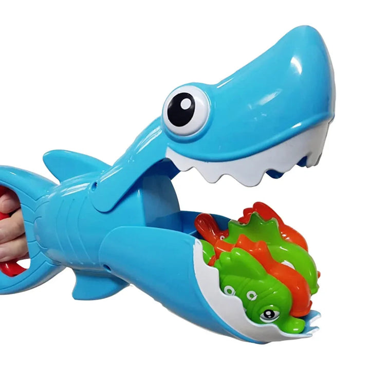 Blue shark bath toy holding green and orange fish in its open mouth