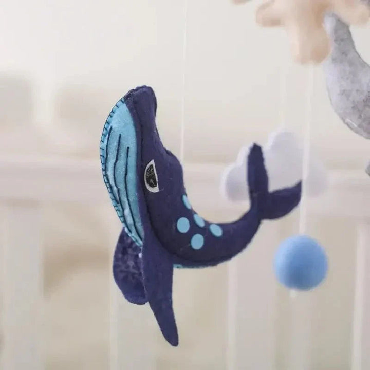 Close-up of a dark blue felt whale with stitched details and light blue spots on the Ocean mobile