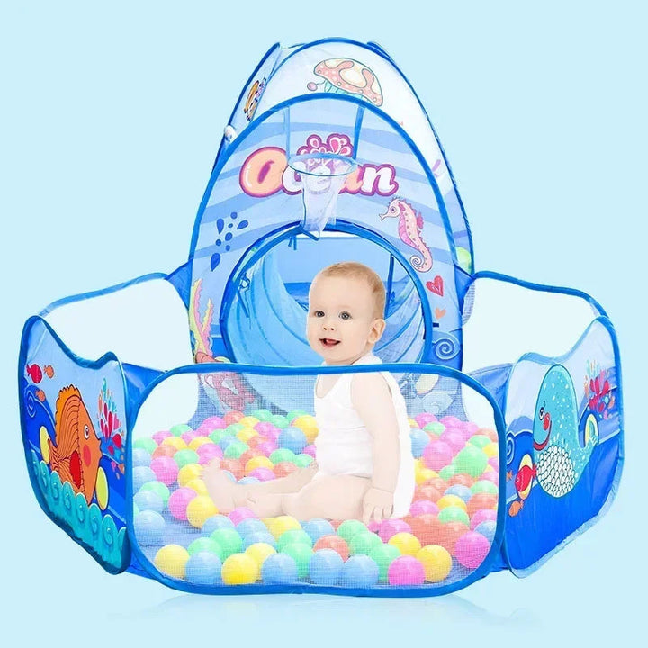 Child sitting among colorful balls in an ocean-print play pit with the tent behind