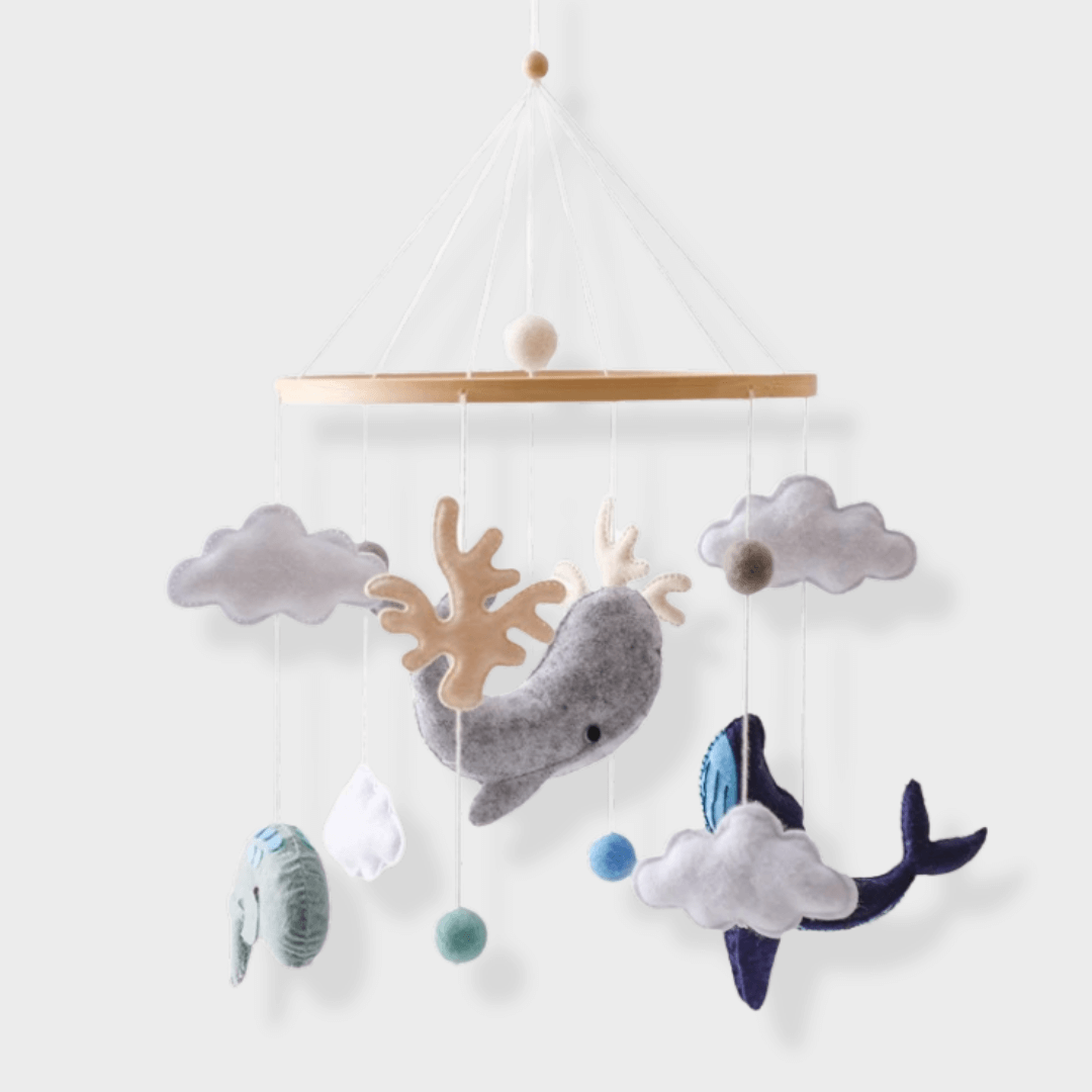 Ocean baby mobile with felt whales, clouds, coral shapes, and colored balls hanging from a wooden ring