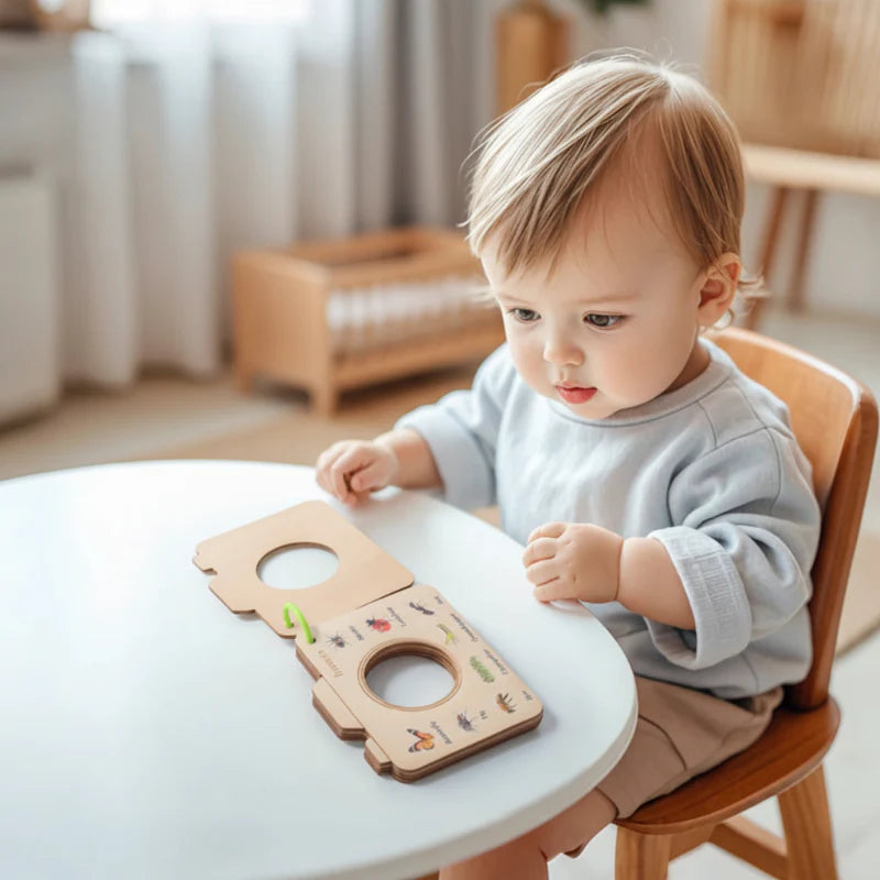 Child examining an open wooden nature viewing frame at a table
