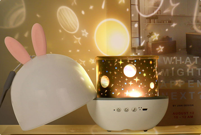 Star projector with its dome cover removed, casting planet and star patterns on the wall