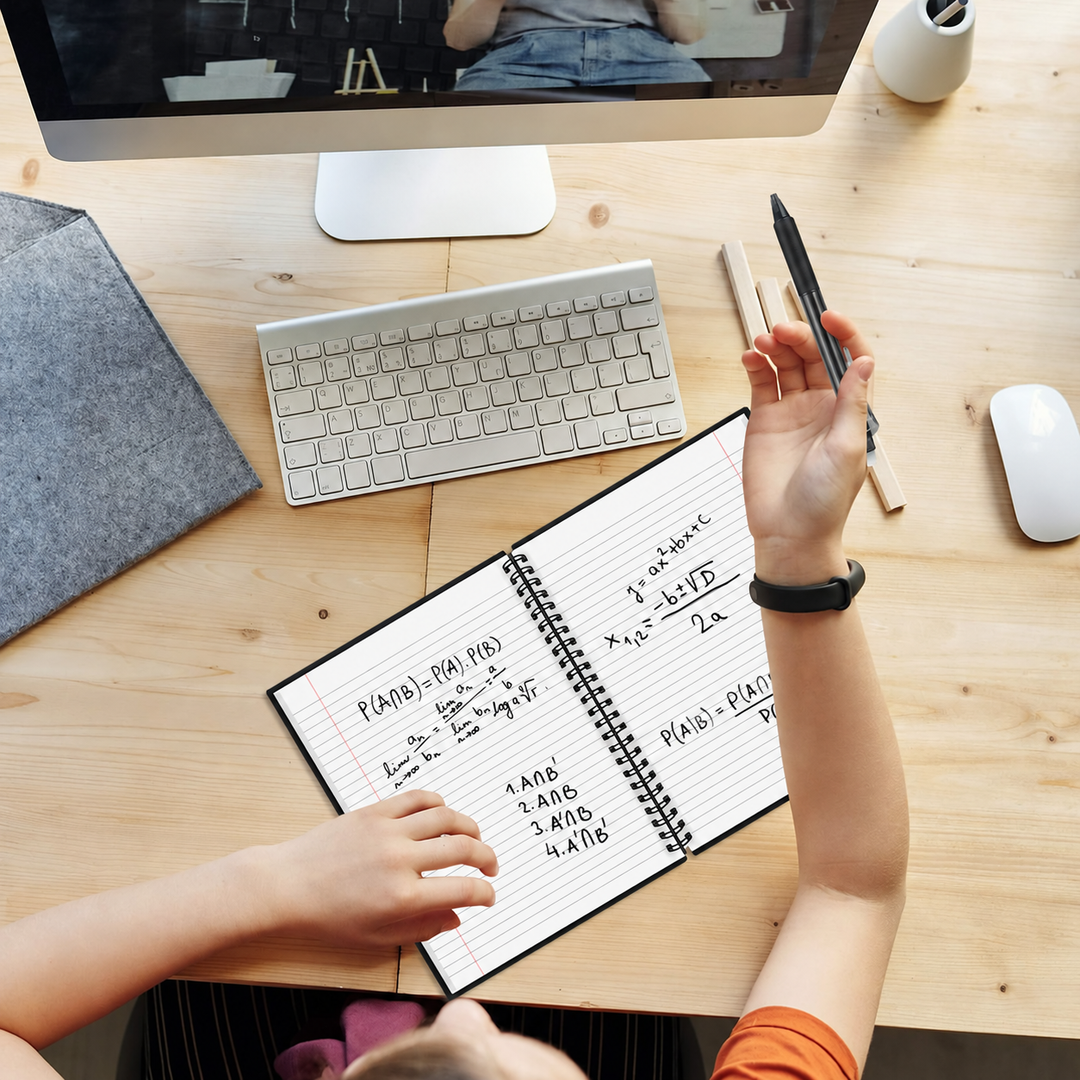 Open spiral notebook with handwritten notes beside a keyboard on a wooden desk