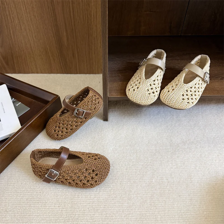 Beige and brown openwork Mary Jane flats beside a wooden cabinet