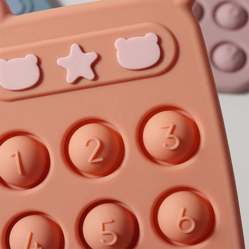 Close-up of raised numbers, bear shapes, and a star on the orange silicone phone