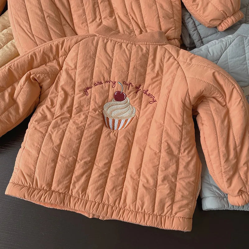 Back of an orange quilted winter coat with cupcake embroidery and a gathered hem