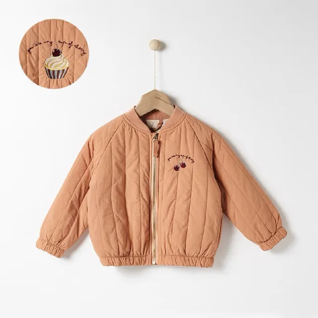 Orange quilted zip-front coat on a hanger, with an inset of the cupcake embroidery on the back
