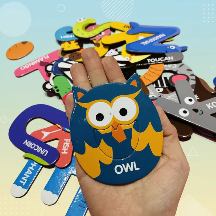 Owl-themed letter magnet resting in a hand beside other animal magnets