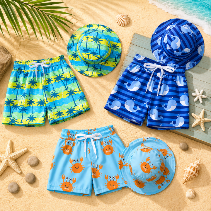 Palm-tree, whale, and crab swim trunks with matching bucket hats arranged on sand