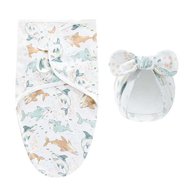 White swaddle blanket and matching bow hat with a pastel shark pattern