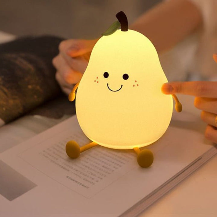 Glowing pear-shaped night light on an open book with a hand touching its side