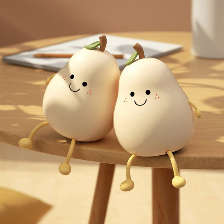Two unlit pear-shaped night lights with smiling faces and dangling legs on a wooden table