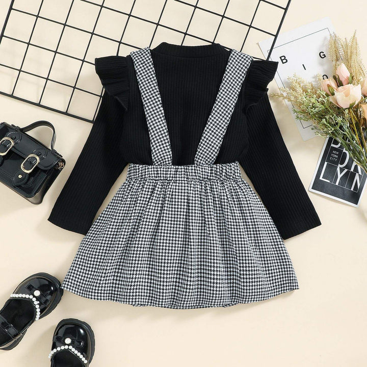 Back view of the houndstooth pinafore skirt showing wide straps and a gathered waistband over the black top.
