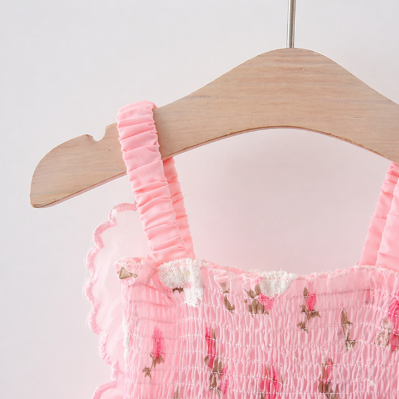 Ruffled pink dress strap and smocked floral neckline on a wooden hanger