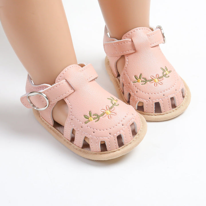 Pink floral baby sandals with cutout toes and light-colored soles on mannequin feet
