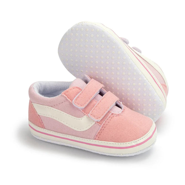 Pink baby sneakers showing hook-and-loop straps and a dotted sole