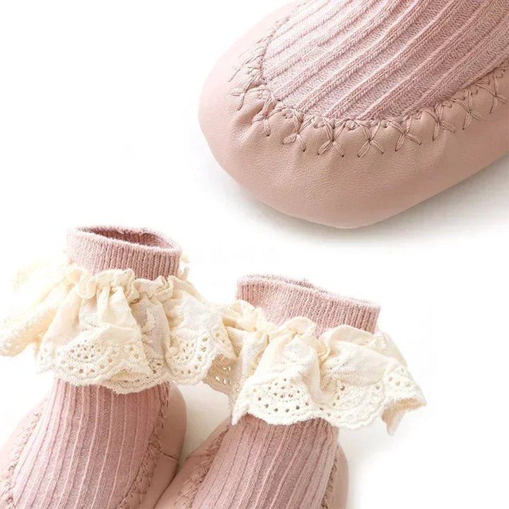 Pink baby sock shoes with a close-up of the stitched toe and ribbed cotton upper