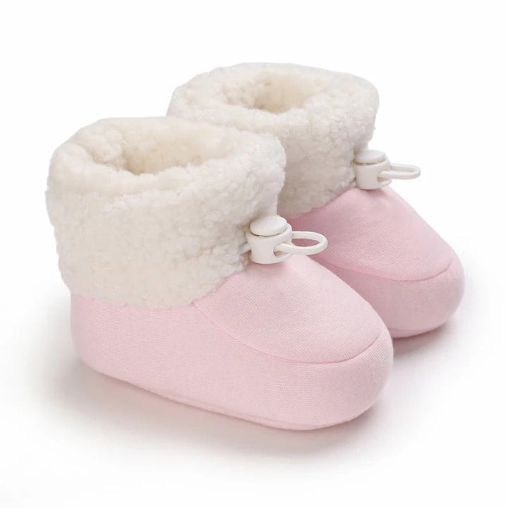 Pink baby winter boots standing side by side with fluffy white cuffs
