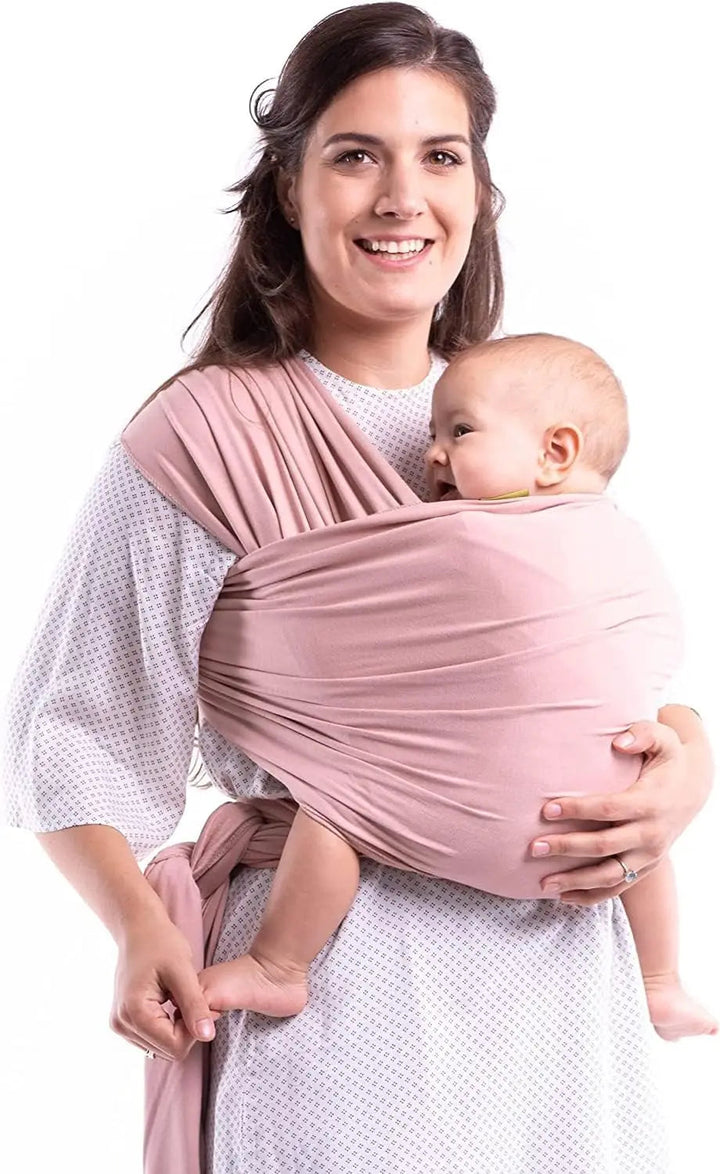 Pink baby wrap carrier worn across the shoulders and tied at the waist for front carrying.