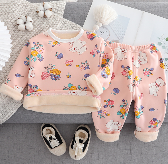 Pink bear-and-flower pajama set with cream trim, arranged on a gray couch