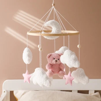 Pink bear baby mobile with white clouds, pink stars and a crescent moon above a crib