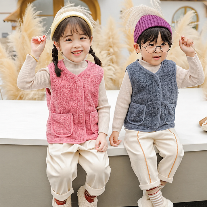 Two children wearing pink and blue fleece vests over long-sleeve shirts.