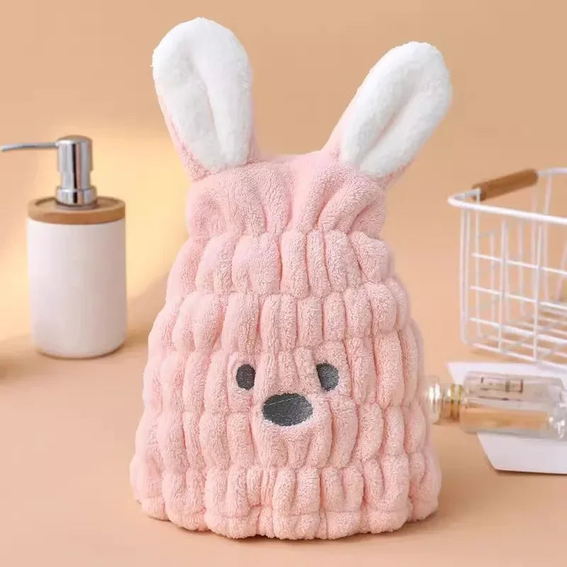 Pink microfiber hair-drying cap with white bunny ears on a bathroom counter